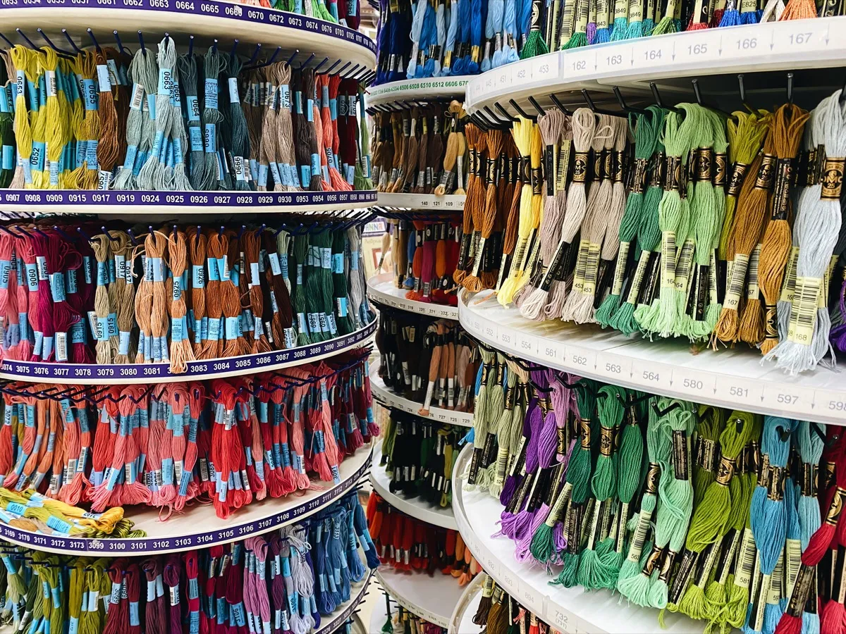 Craft store display racks filled with hundreds of embroidery floss skeins organized by color number